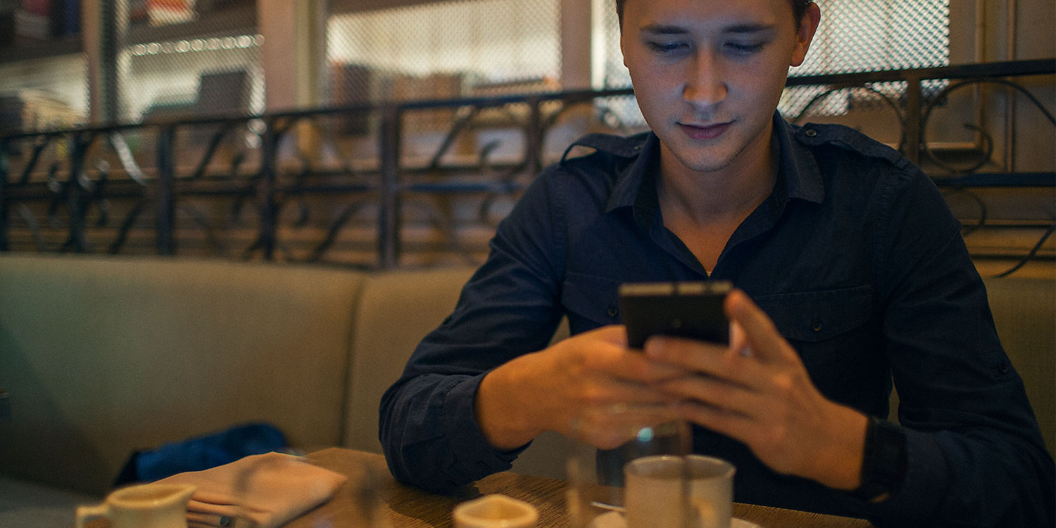 Daniel Bostic using his phone at a café